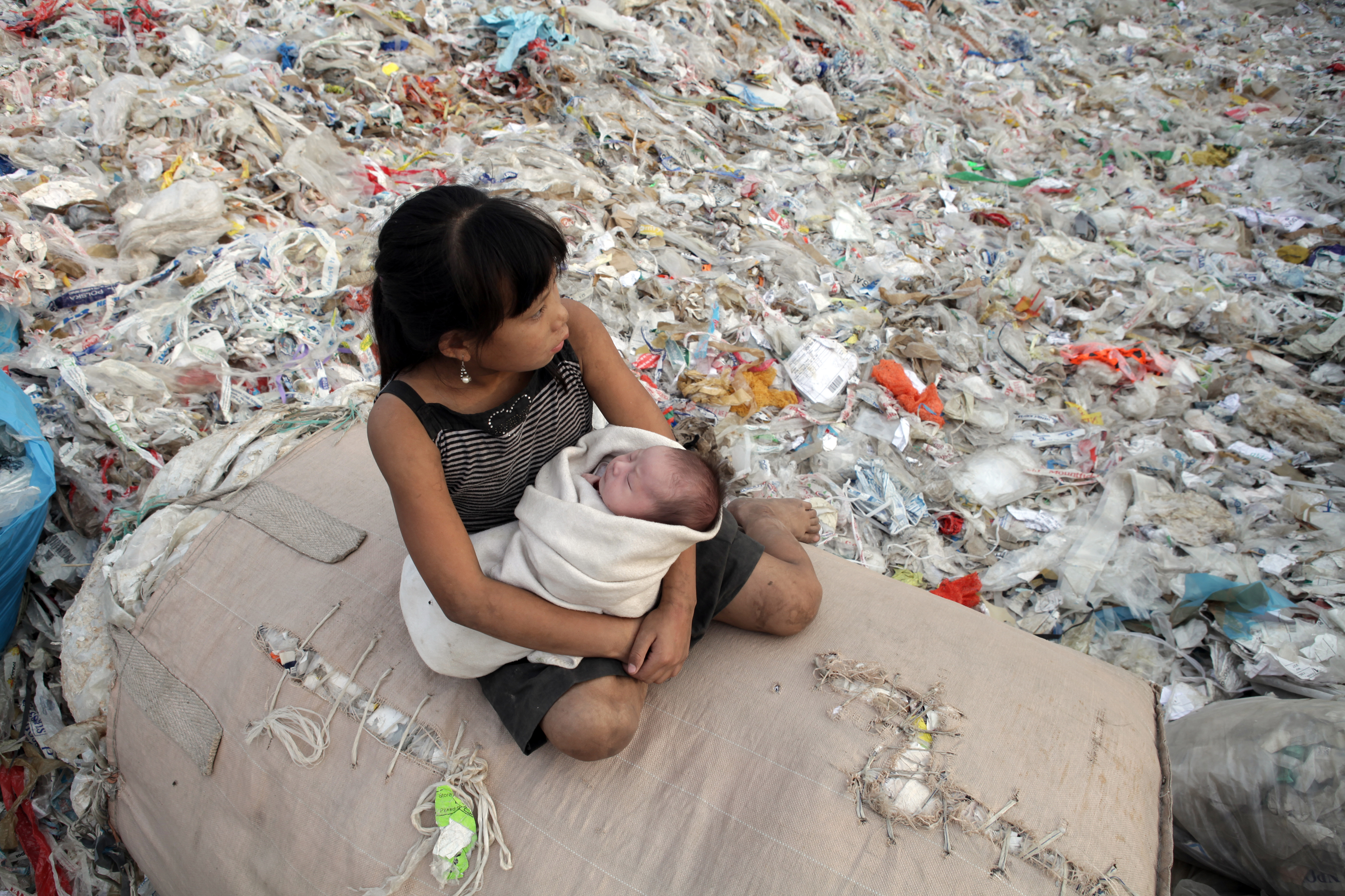 Plastic China documentary – girl sitting on a pile of recycling